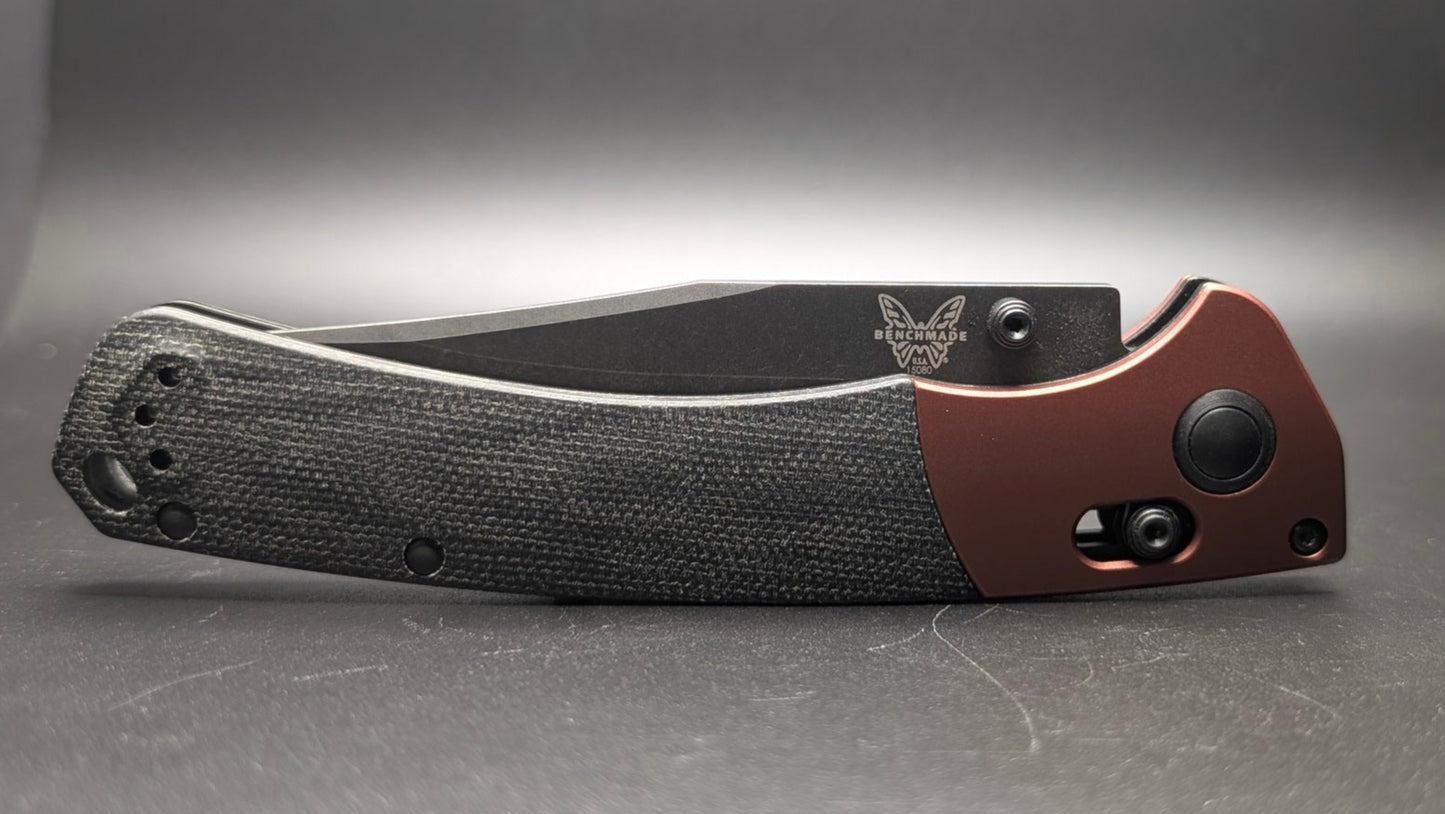 Folding knife with black handle and brown blade on a gray background