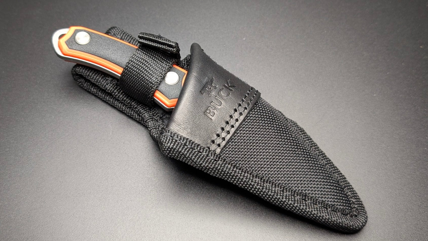 Orange knife with sheath on a dark gray background