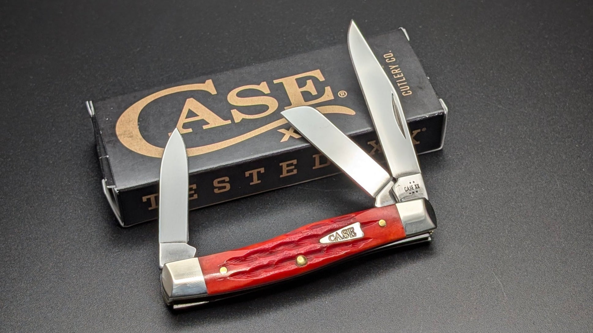 Case Indian Paint Brush Bone Kinfolks Jig Medium Stockman Model #42321 Pattern (63032 SS) on a drak gray surface open 3 blades