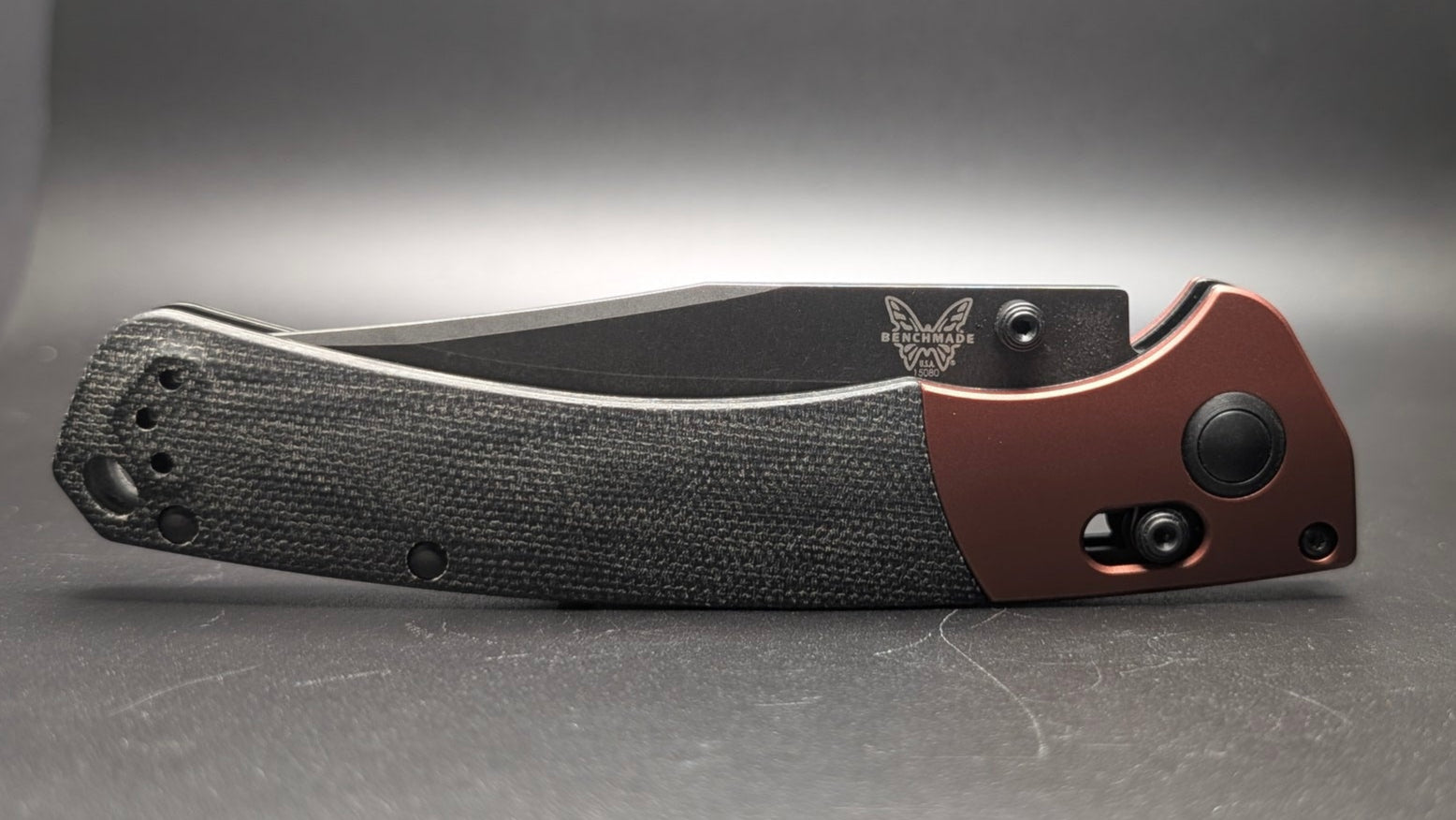 Folding knife with black handle and brown blade on a gray background