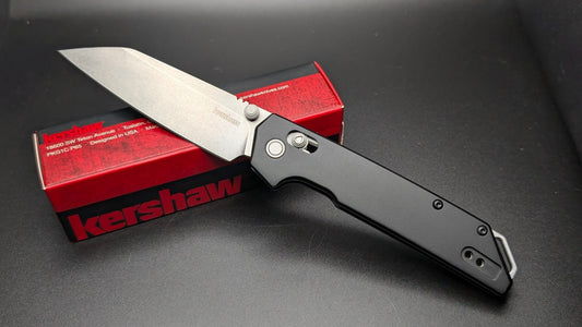 Kershaw folding knife on a dark surface with a red Kershaw box.