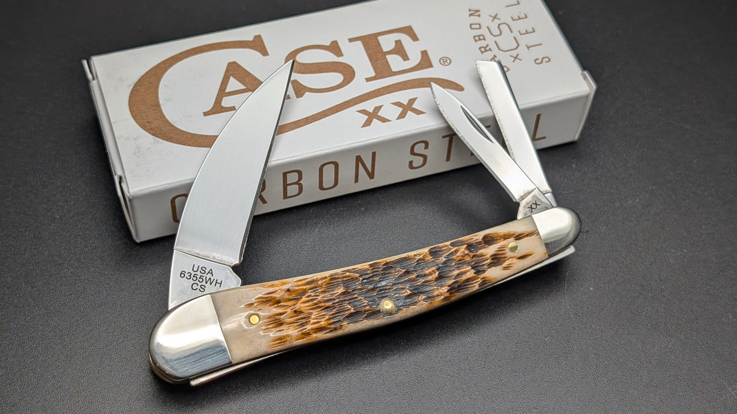 Foldable knife with Amber Bone handle on a gray surface next to a Case brand box.