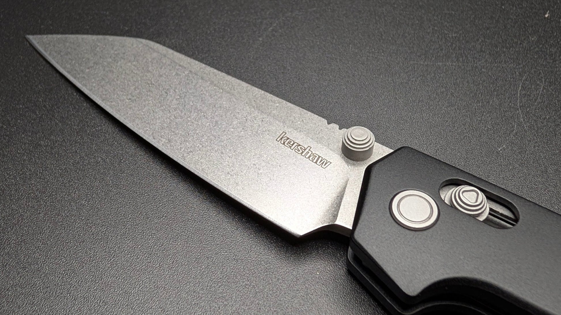 Folding knife with a black handle and silver blade on a dark background