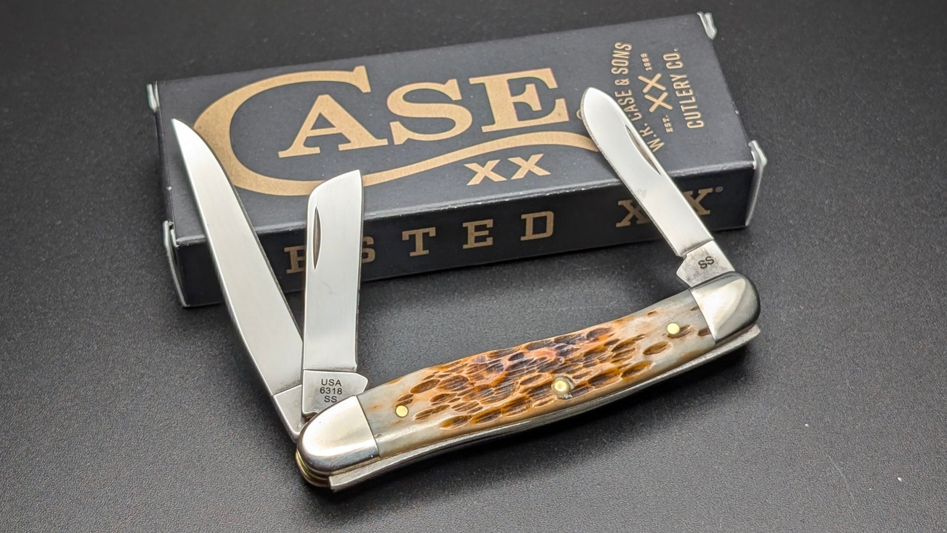 Case Amber Bone Peach seed Jig Medium Stockman Model #00042 Pattern (6318 SS) Open Back on a Gray Surface with a box
