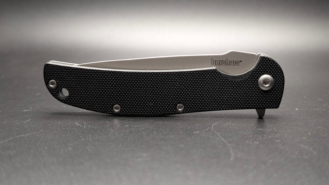 Black folding knife on a gray background