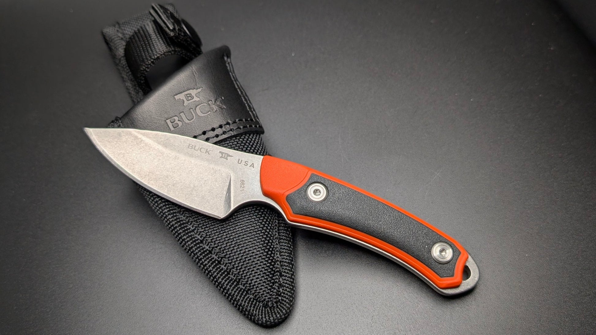 Fixed Blade knife with black sheath on a dark surface