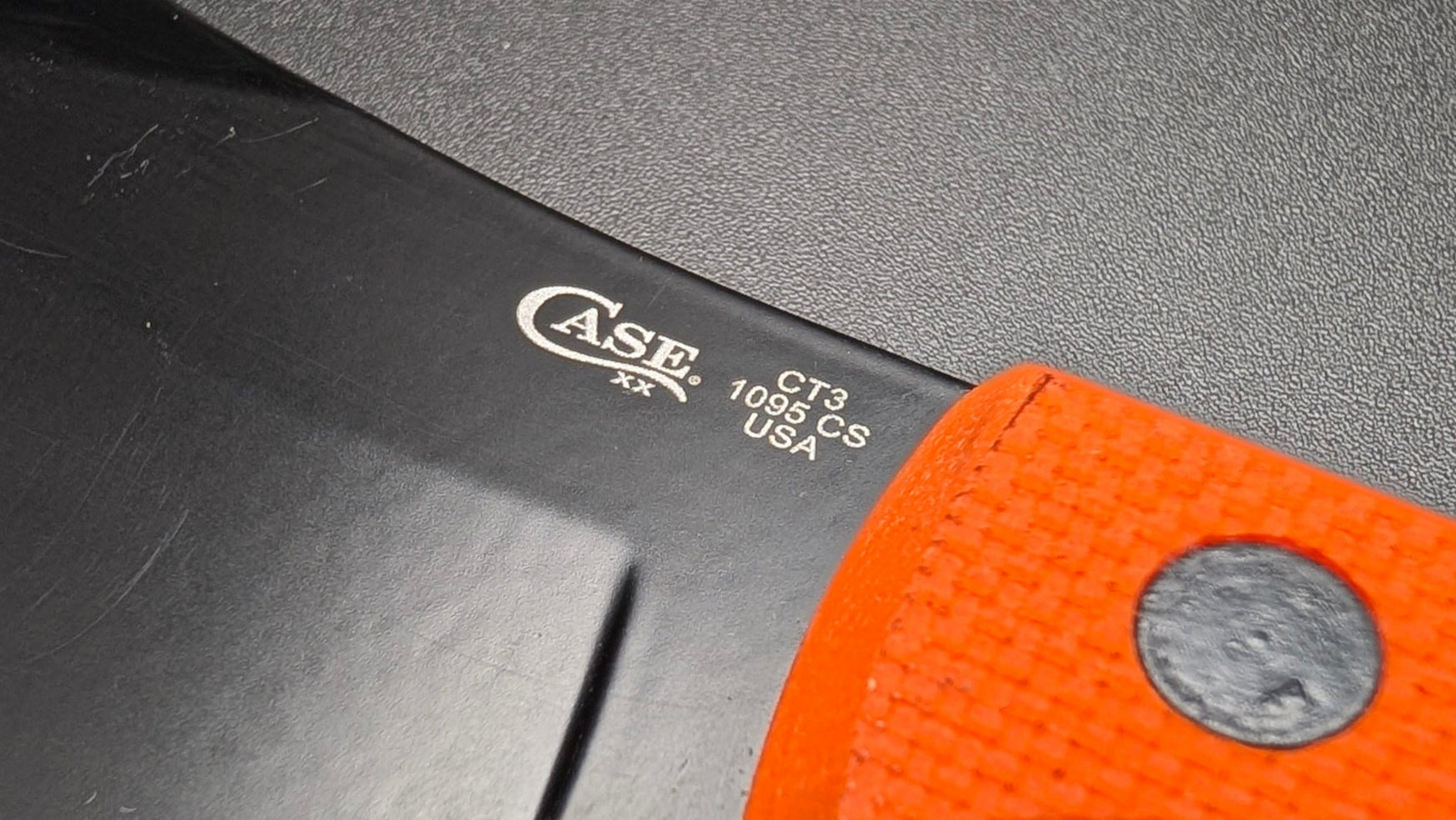 Knife with orange handle and visible Asee branding on a dark background