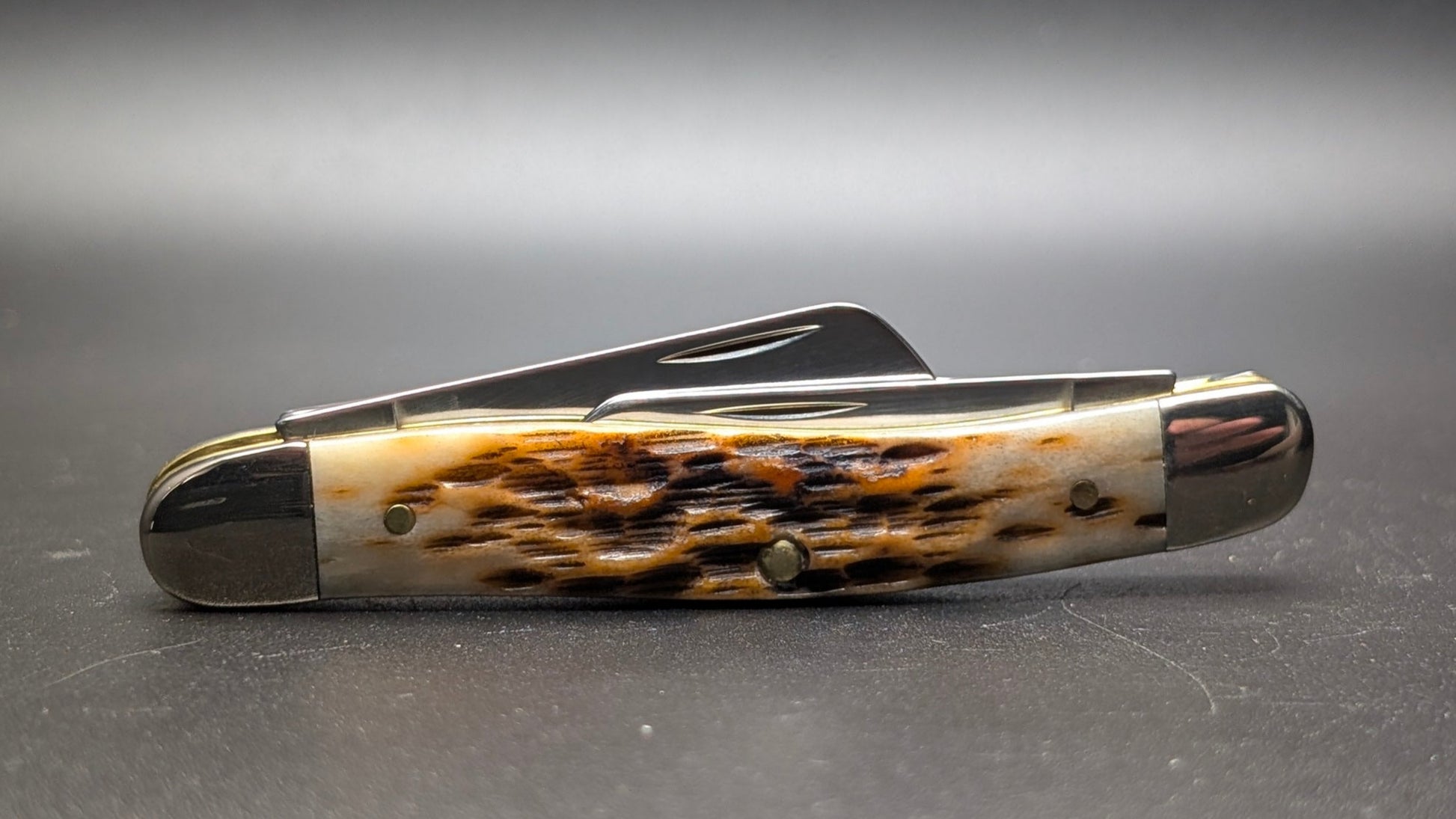 Case Amber Bone Peach seed Jig Medium Stockman Model #00042 Pattern (6318 SS) Closed Back on a Gray Surface