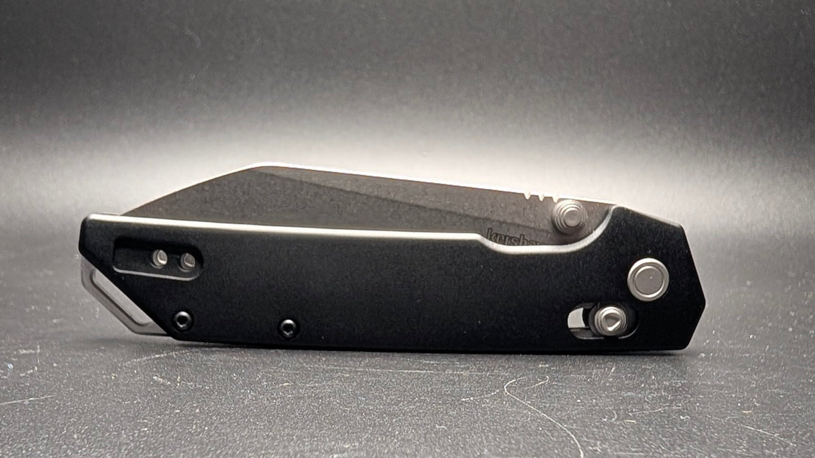 Black pocket knife on a gray surface with a dark background