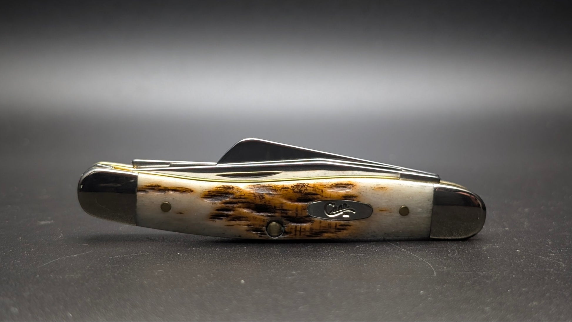 Case Amber Bone Peach seed Jig Medium Stockman Model #00042 Pattern (6318 SS) Closed Front on a Gray Surface