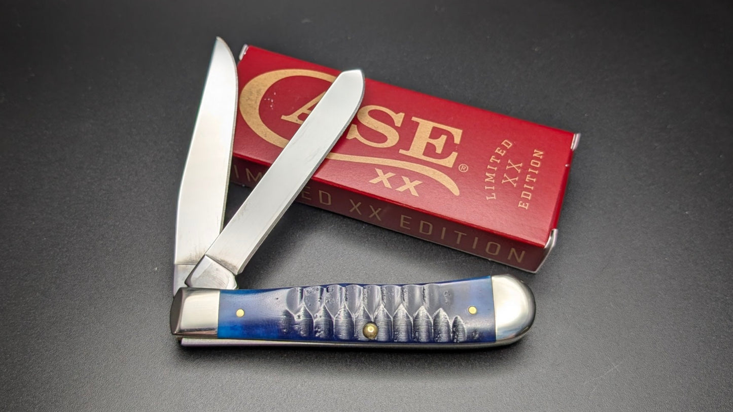 Folding knife with blue handle and silver blade on a black surface, next to a red 'Case' knife box.