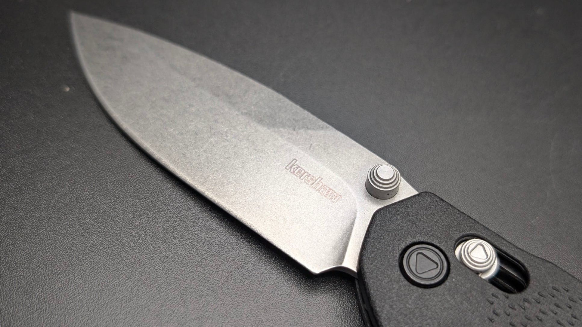 Folding knife with a black handle on a dark gray background