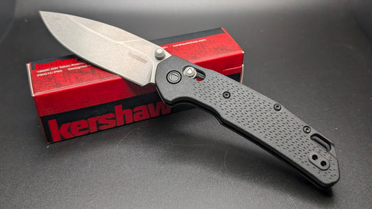 Folding knife with a Kershaw brand box on a dark surface
