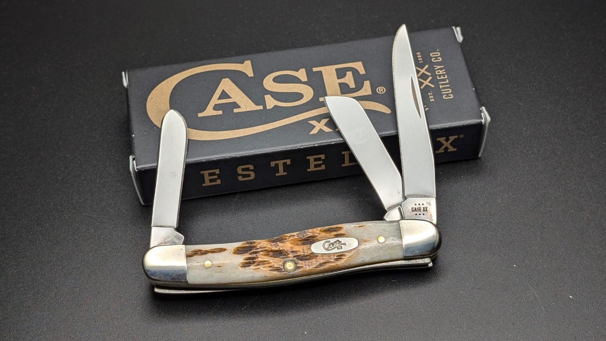 Case Amber Bone Peach seed Jig Medium Stockman Model #00042 Pattern (6318 SS) Open Front on a Gray Surface with Box
