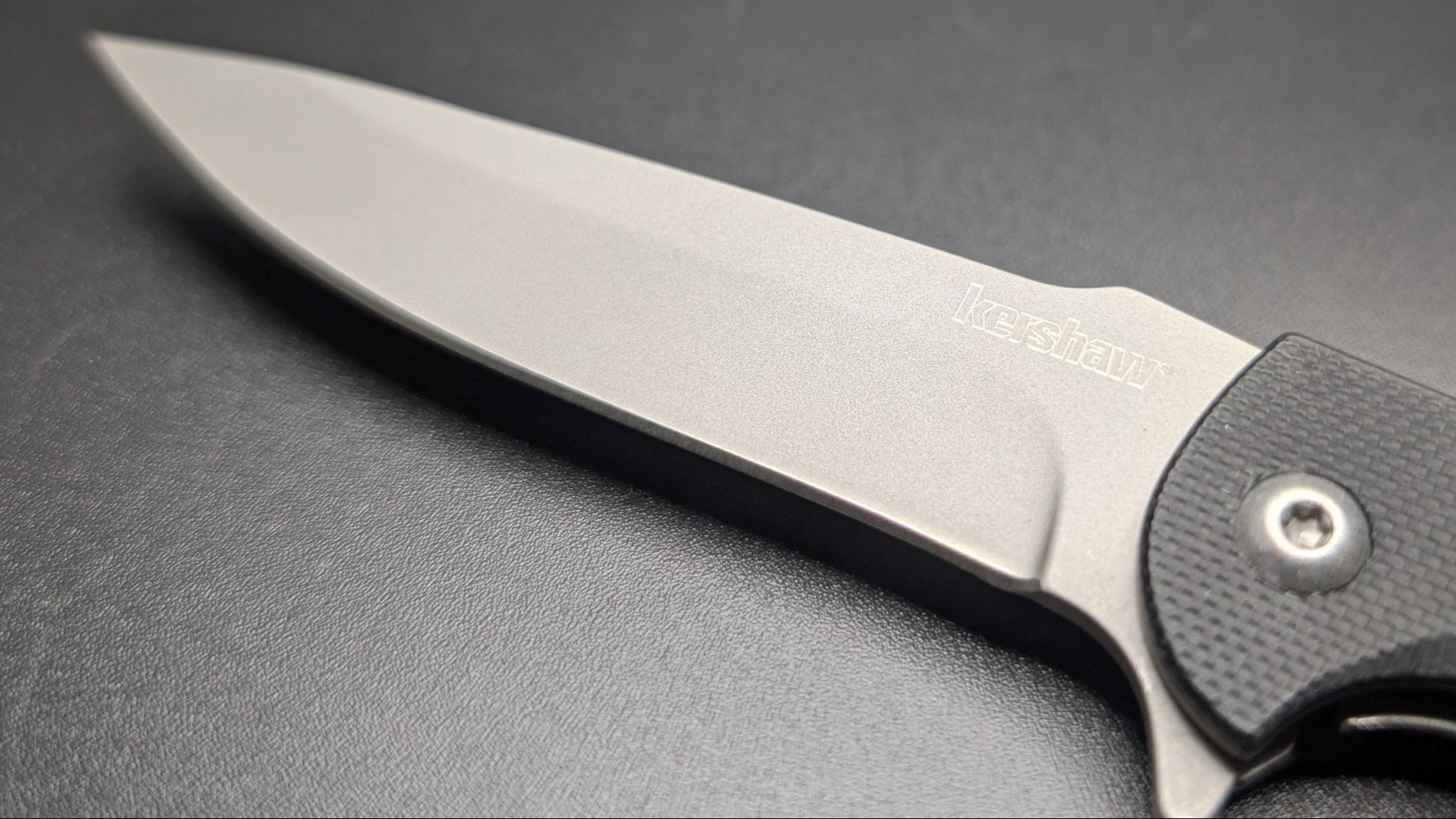 Folding knife with a black handle on a gray surface